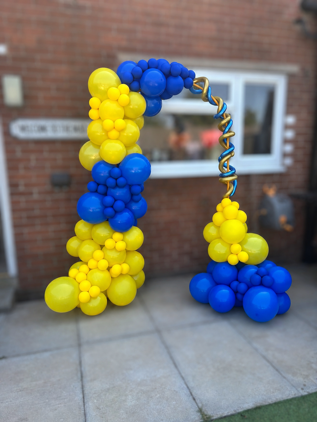 Yellow and blue balloon arch at an outdoor event